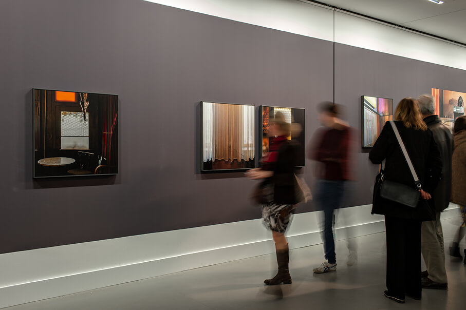 Ansicht der Eröffnungsveranstaltung der Ausstellung "Chez Icke" mit Ausstellungsbesuchern, die Kneipenfotografien betrachten