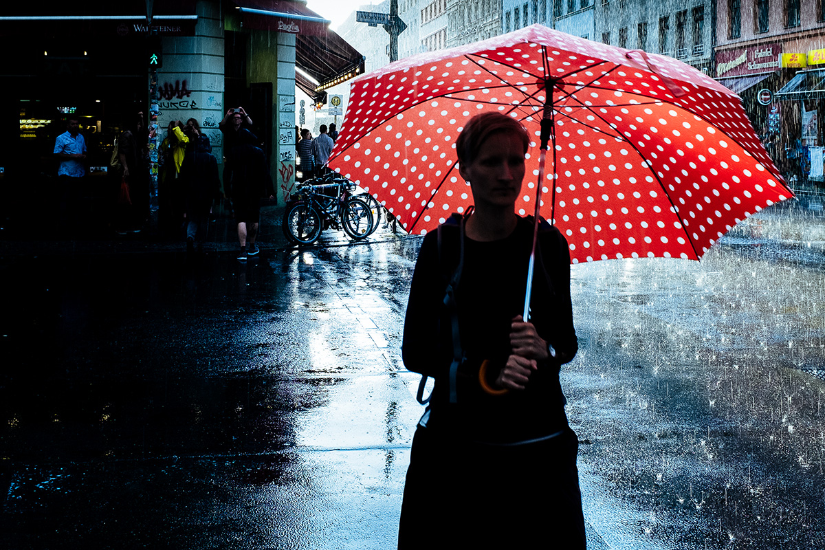 Frau mit rotem Regenschirm auf dunkler Straße
